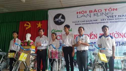 Đại diện lãnh đạo Hội Bảo tồn lan rừng Việt Nam và chính quyền địa phương  trao tặng xe đạp và tập cho học sinh.
